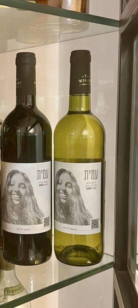 שני בקבוקי יין ועליהם דיוקנה של עמית, שמה, והכיתוב ״פשוט להיות״